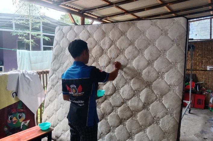 Riko saat mencuci springbed milik pelanggannya.