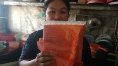 Sri dengan sebungkus tas kresek yang baru saja dibelinya.