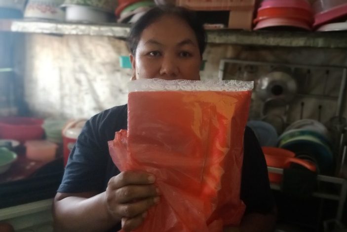 Sri dengan sebungkus tas kresek yang baru saja dibelinya.