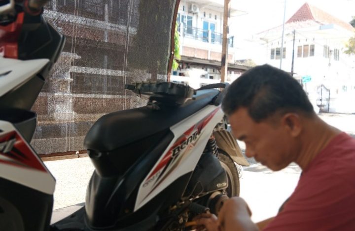 Maun saat melakukan reparasi motor pelanggannya.